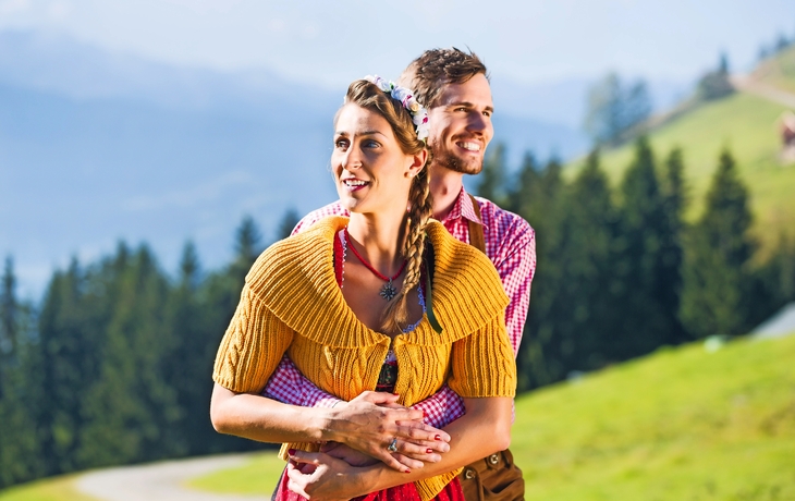 Paar in Tracht im Urlaub auf Alpen Berggipfel